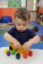 toddler_playing_with_colored_cylinders_creative_kids_childcare_centers_beekman-306x450