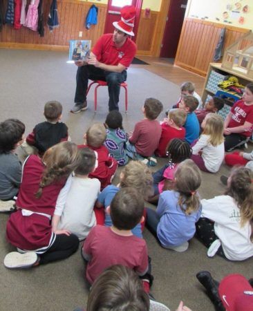 visitor_reading_book_with_cat_in_the_hat_hat_cadence_academy_preschool_fayetteville_ar-366x450