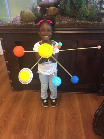 A child holding a model of the solar system
