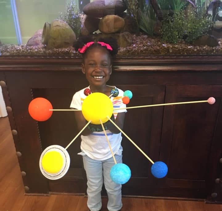 A child holding a model of the solar system