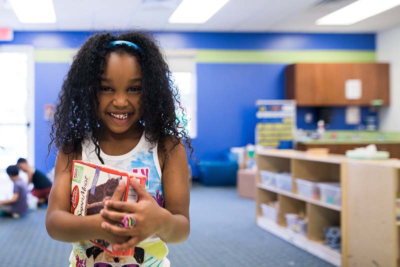 a photo of a child holding a baking kit indoors