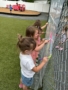 little children painting on wall outside covered with plastic canvas