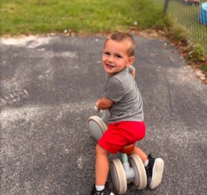 child riding bike looking backwards at person taking the picture