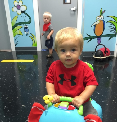 little boy looking up while on little toy
