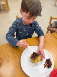 child decorating cupcake with frosting at cadence academy preschool 453 pond