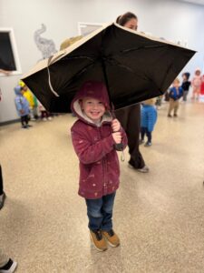 child smiling holding umbrella inside at cadence academy preschool 453 pond