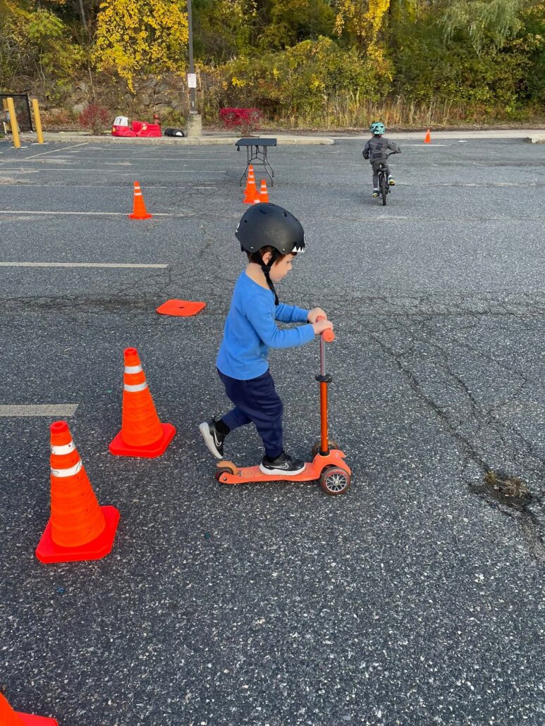 child scootering outside inside of cones at cadence academy preschool 453 pond