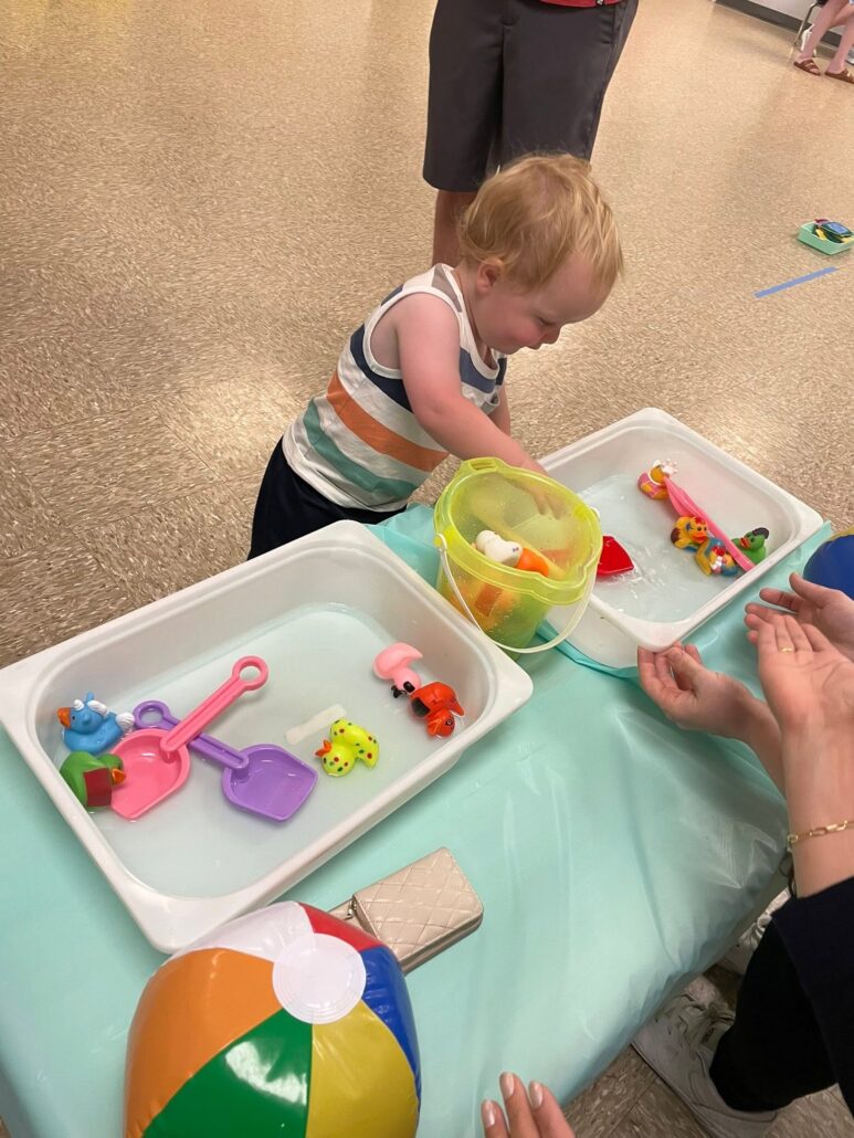child playing with summer toys in water bin at cadence academy preschool 453 pond