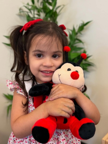 female child hugging stuffed animal ladybug at little big minds uptown