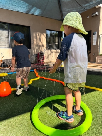 male children playing in water outside little big minds uptown