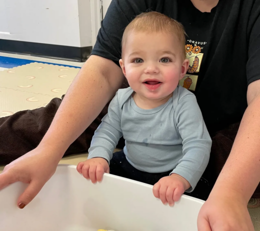Child smiling in teachers lap at preschool and daycare at cadence academy preschool 452 south street