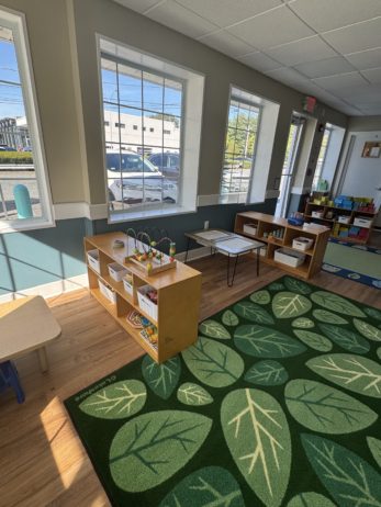 Inside Cadence Academy Preschool small cubbies with learning materials in brightly lit classroom windows and rug with fun pattern in the middle