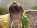 a child smelling a plant outside