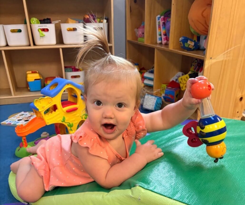 Child playing with toy on ground during tummy time at the professors learning center daycare and preschool elkhorn NE 509