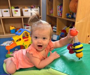 Child playing with toy on ground during tummy time at the professors learning center daycare and preschool elkhorn NE 509