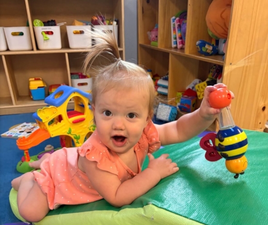 Child playing with toy on ground during tummy time at the professors learning center daycare and preschool elkhorn NE 509