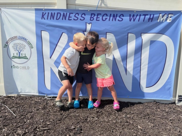 children smiling and hugging in front of kind child sign at the professors learning center daycare and preschool elkhorn NE 509