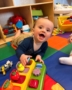 Infant smiling with hand on learning toy at the professors learning center daycare and preschool elkhorn NE 509