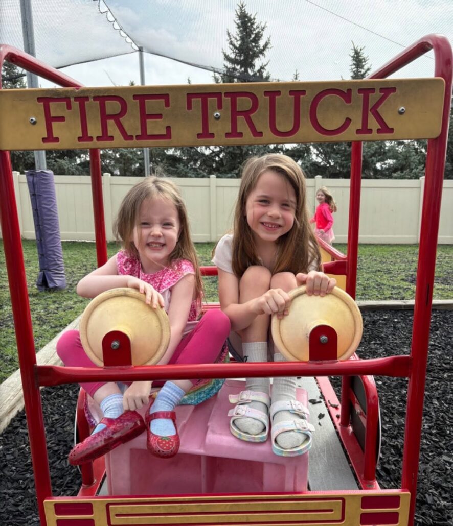 Children posing on playground smiling in firetruck play structure at the professors learning center daycare and preschool elkhorn NE 509