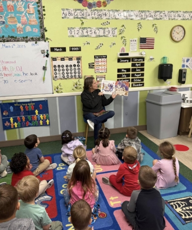 children engaged in teacher reading book at watch me grow power