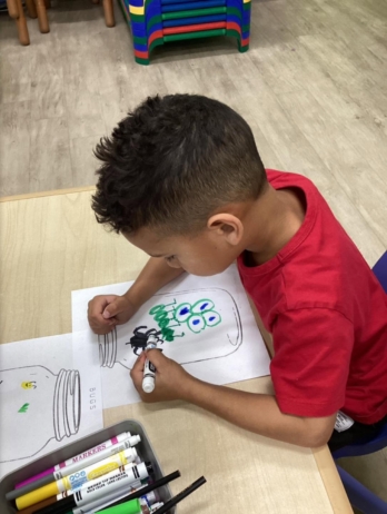 male child drawing at desk at watch me grow riggs