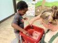 male child learning through hands on activity with teacher at watch me grow riggs
