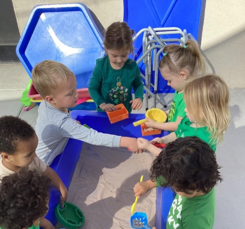 multiple children around sandbox at watch me grow riggs