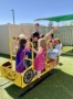 multiple children playing with teacher outside on playground equipment at watch me grow riggs