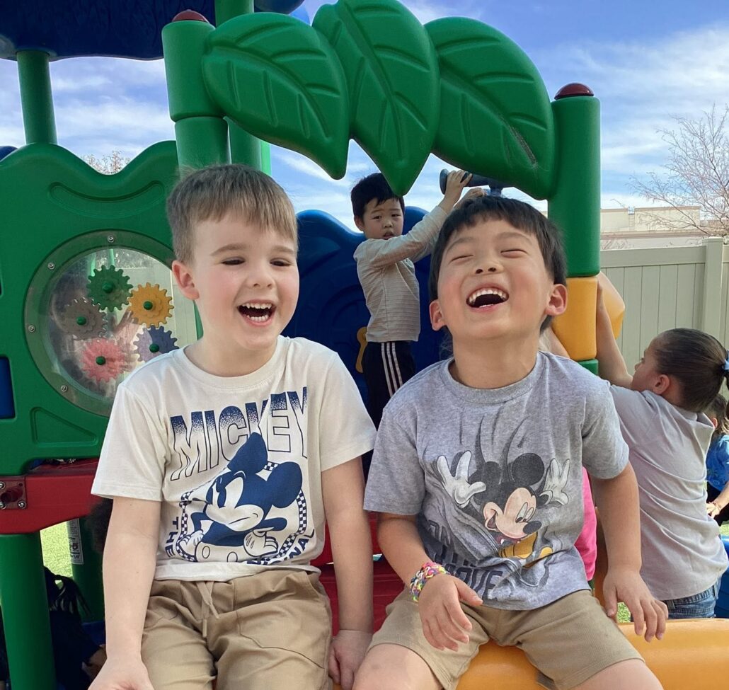 two male children laughing on playground at watch me grow riggs