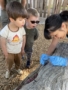 preschool children observing and exploring natural materials with teacher outdoors