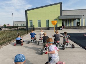 Children playing outside with school in background Generation Next Bondurant