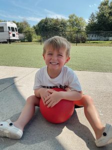 Child outside holding ball and smiling at camera Generation Next Bondurant