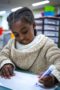 elementary girl in afterschool program practicing writing on a whiteboard in a classroom