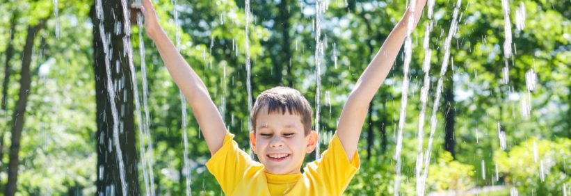 child in yellow shirt playing in the splash pad located at the daycare in greensboro north carolina