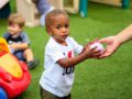Small child in toddler care center being handed a baseball photo taken in greensboro north carolina